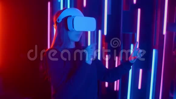 无脸女士戴VR耳机在黑暗空间与霓虹灯用户转过头侧看虚拟视频的预览图