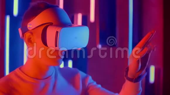 在霓虹灯中使用VR眼镜的年轻人视频的预览图