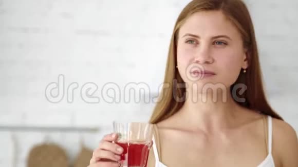 漂亮的女孩从杯子里喝新鲜的葡萄柚汁视频的预览图