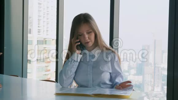 严肃的女商人坐在办公室用智能手机和客户交谈视频的预览图