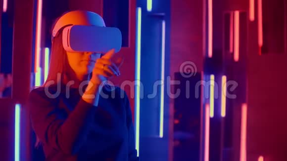女人戴着VR耳机从一边到另一边快速倾斜同时在黑暗的空间里玩照亮了霓虹灯视频的预览图
