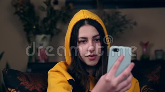 年轻快乐的白种人女人穿着黄色夹克用手机与朋友在线视频聊天并在博客上写字视频的预览图