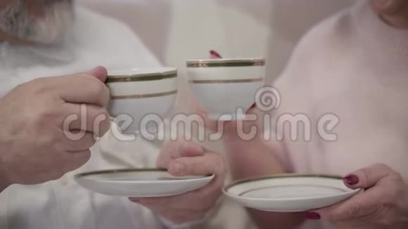 男女白种人的特写双手紧握茶杯快乐成熟的配偶在家喝茶视频的预览图