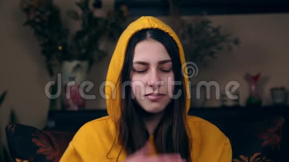 一个穿黄色夹克的年轻女孩坐在椅子上咳嗽年轻女性咳嗽打喷嚏女性有冠状病毒视频的预览图