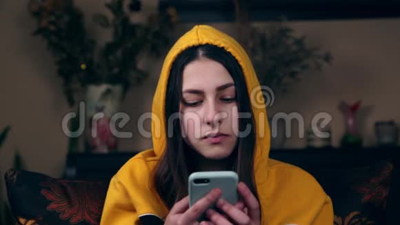年轻女子坐在椅子上在一个舒适的房间里用手机聊天的肖像家庭气氛不错视频的预览图