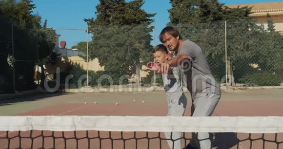 打网球的孩子父亲和儿子练习打网球一起积极休闲视频的预览图