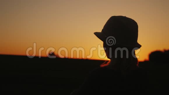 一位年轻女子欣赏日落的剪影展望未来视频的预览图