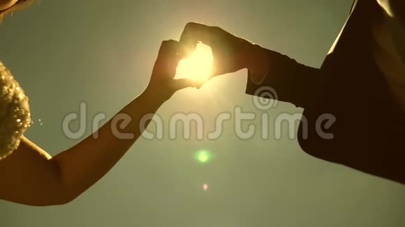 手里拿着太阳一对恩爱夫妻的剪影用双手在地平线上的太阳对面做一个心的象征视频的预览图