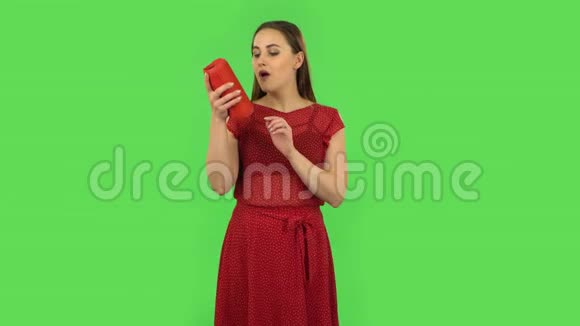 穿着红色裙子的温柔女孩正在用蓝牙便携式扬声器和舞蹈听音乐绿色屏幕视频的预览图