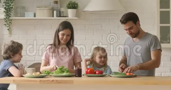 快乐的金发兄弟姐妹孩子在厨房看着父母准备食物视频的预览图