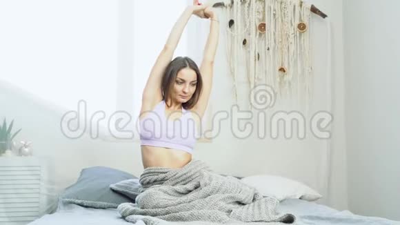 年轻迷人的女人在家里的卧室里伸展身体享受早上好视频的预览图