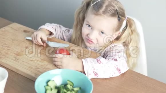 一个可爱的小女孩切番茄做蔬菜沙拉视频的预览图