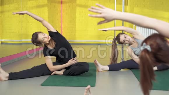 一群年轻的适合女性在瑜伽课上和教练一起做伸展课视频的预览图