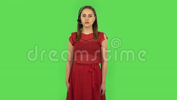 温柔的女孩穿着红色的衣服在耳机帮助客户服务绿色屏幕视频的预览图