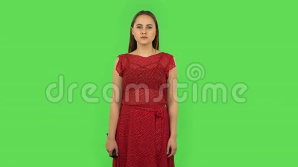 一个穿着红色连衣裙手里拿着电视遥控器打开电视的小女孩绿色屏幕视频的预览图