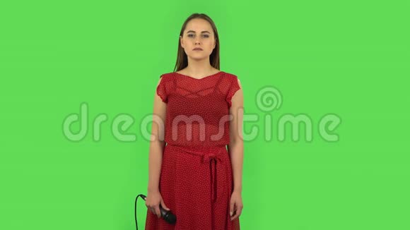 穿着红色衣服的温柔女孩正对着麦克风唱歌并随着音乐的节拍移动绿色屏幕视频的预览图