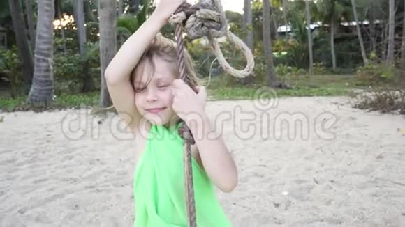微笑小女孩在海滩上的绳索上摇摆视频的预览图