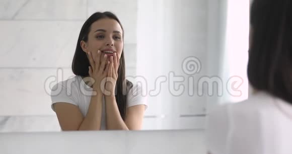 年轻快乐的女人触摸柔软皮肤的镜子反射视频的预览图