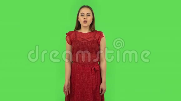 穿着红衣服的娇嫩女孩受着高温天气的折磨正在用手降温绿色屏幕视频的预览图