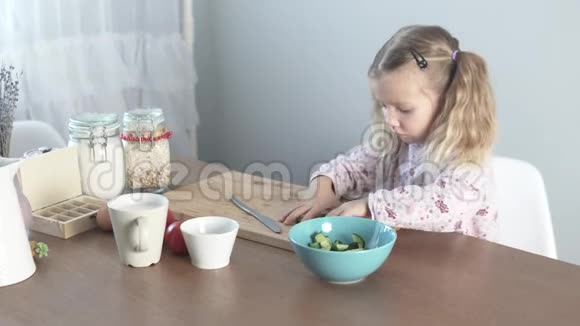 一个小女孩把剁碎的黄瓜放在色拉盘里视频的预览图