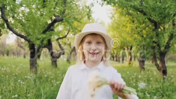一个带着蒲公英花束的快乐女孩的肖像跑向镜头大笑视频的预览图