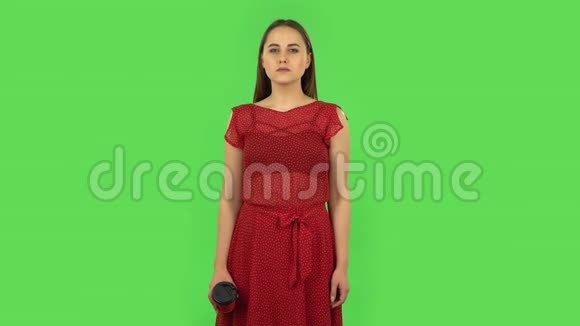 穿着红色裙子的温柔女孩喝着令人讨厌的咖啡感到厌恶绿色屏幕视频的预览图