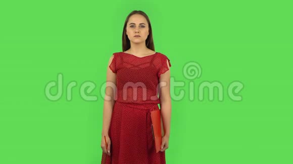 穿红色衣服的温柔女孩用pensil把文件填在红色文件夹里绿色屏幕视频的预览图