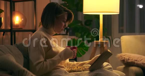 女人看书晚上在沙发上喝咖啡视频的预览图