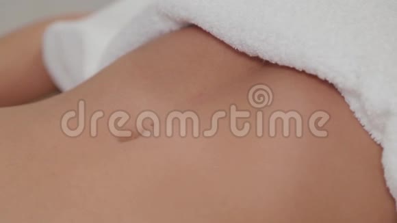 女性按摩治疗师在一个年轻女孩的胃上注入按摩油视频的预览图