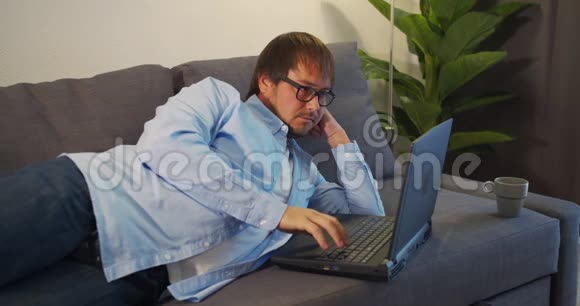 在电脑前努力工作的帅哥摘下眼镜揉了揉眼睛办公室职员自由职业者工作狂视频的预览图