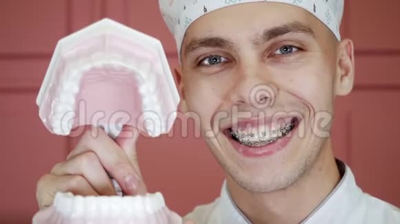 一个年轻人带着牙套笑着拍下颚植入物的肖像视频的预览图