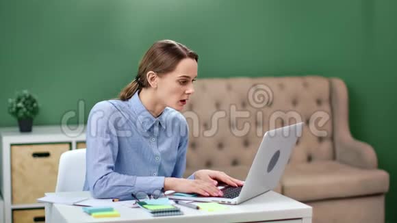 快乐的商务女性看着笔记本电脑庆祝成功的交易4k龙红相机视频的预览图