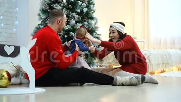 圣诞树旁美丽的家庭快乐爸爸妈妈和小宝宝视频的预览图