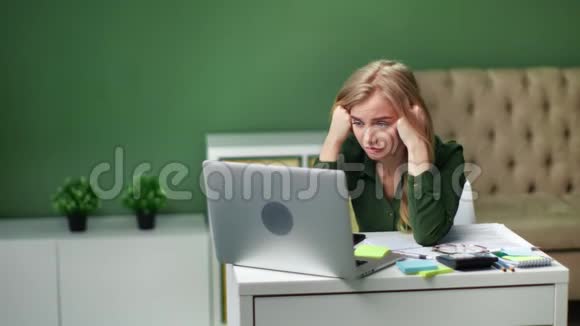坐在笔记本电脑前头痛的年轻女子4K红色摄像机拍摄视频的预览图
