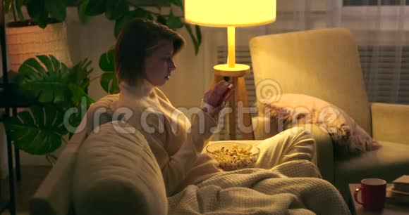 女人晚上用手机吃爆米花视频的预览图