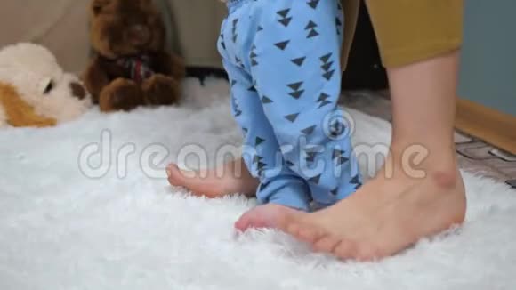 妈妈和宝宝的脚从右向左踏婴儿第一步的概念慢镜头和特写镜头视频的预览图