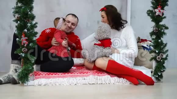 年轻的白种人父母在圣诞假期用可爱的泰迪熊玩他们可爱的女婴视频的预览图