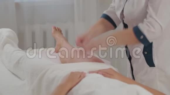 女按摩师在一个年轻女孩的整个腿部做按摩视频的预览图