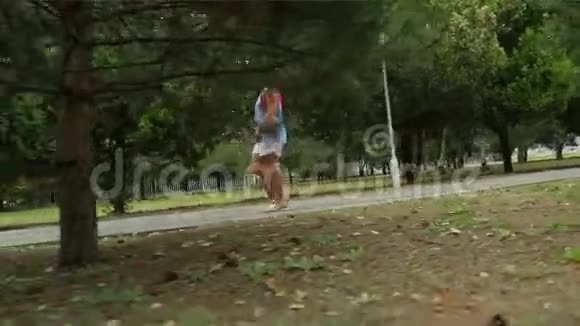 一个女人在公园里沿着绿色的小巷散步视频的预览图
