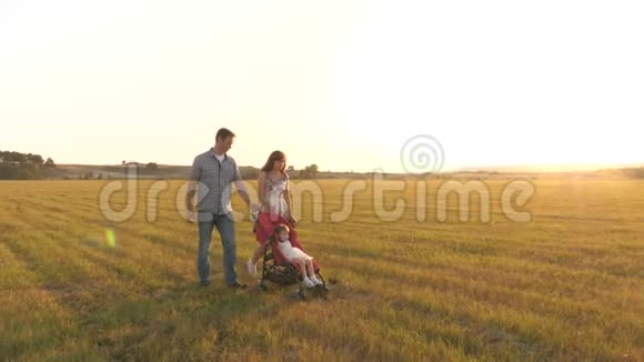 在大自然中和一个小孩子散步小女儿在公园的阳光下牵着爸爸和妈妈的手跳着视频的预览图