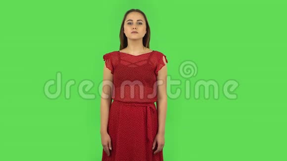 穿着红色衣服的温柔女孩正在说话并指着侧手寻找什么复制空间绿色屏幕视频的预览图