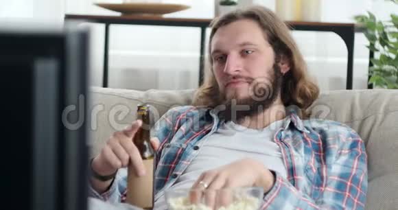 在家看电影的人拿着啤酒和爆米花视频的预览图