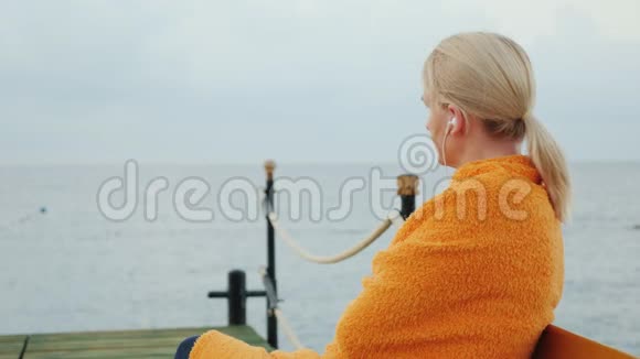 女人用毛巾裹着自己等待太阳从海面升起视频的预览图