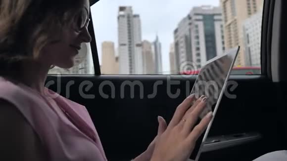 一个坐在车里的女孩在迪拜开车时用平板电脑工作视频的预览图