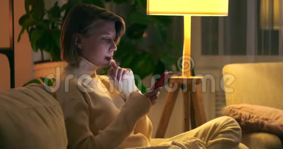 晚上在沙发上用手机聊天的女人视频的预览图