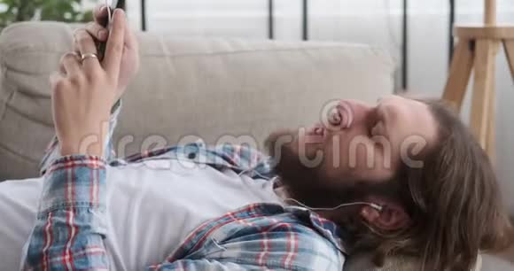 男人在沙发上用手机听音乐视频的预览图