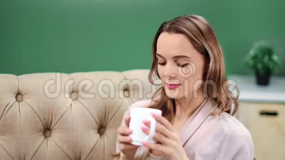 愉悦的女人喝茶在沙发上放松有积极的情绪4K红色相机拍摄视频的预览图