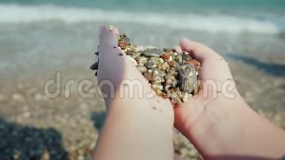女人的手握着一把湿的鹅卵石在海上休息冥想的概念视频的预览图