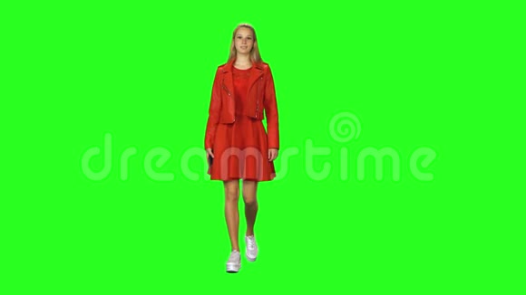 金发女孩在绿屏背景下平静地走着用手机聊天彩色键正视图视频的预览图