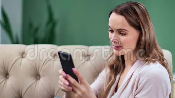 微笑的金发女孩看着手机屏幕聊天4k龙红色摄像机视频的预览图